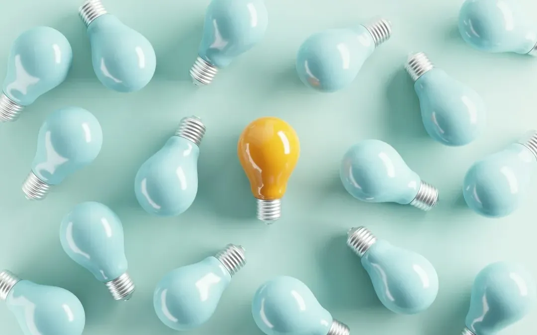 A yellow idea bulb among pale blue light bulbs.