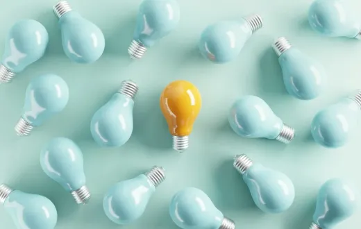 A yellow idea bulb among pale blue light bulbs.