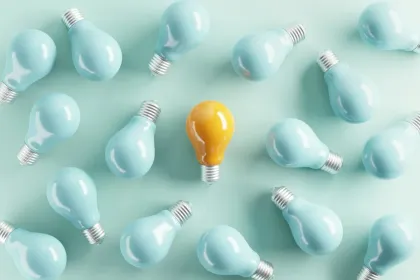 A yellow idea bulb among pale blue light bulbs.